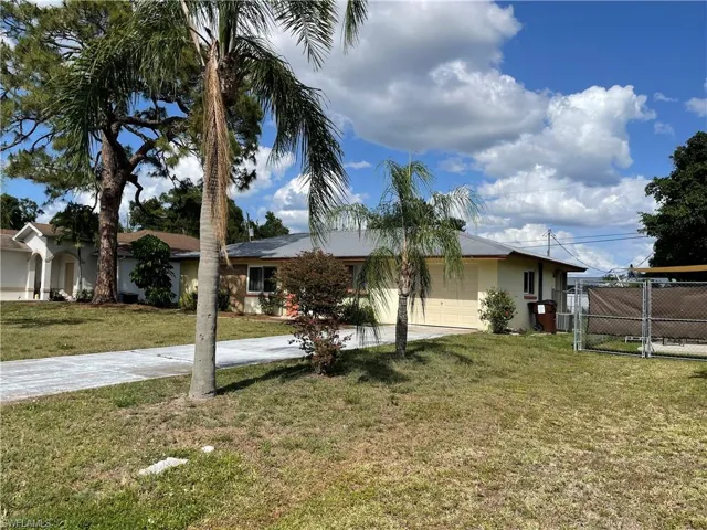 View of front facade featuring a garage, fence, a front lawn, a gate, and driveway