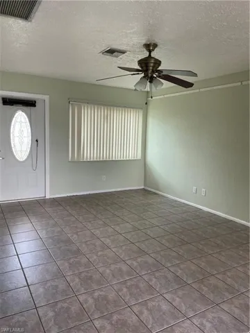 Foyer featuring dark tile patterned flooring, a textured ceiling, ceiling fan, and visible vents