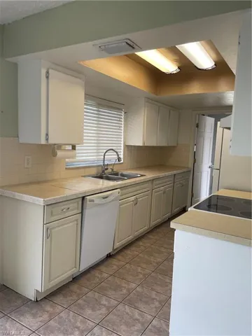 Kitchen featuring light tile patterned floors, visible vents, dishwasher, a sink, and decorative backsplash