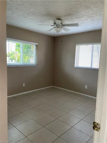 Empty room featuring light tile patterned floors, ceiling fan, and plenty of natural light