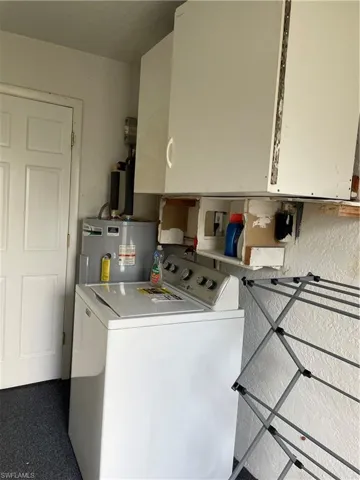 Clothes washing area featuring cabinet space, washer / clothes dryer, and water heater