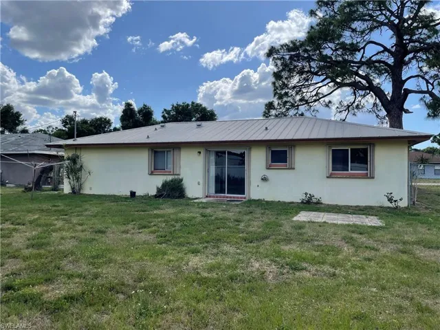 Back of house with stucco siding and a lawn