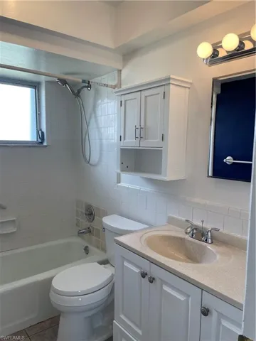 Full bathroom featuring toilet, vanity, shower / bathtub combination, backsplash, and tile patterned floors