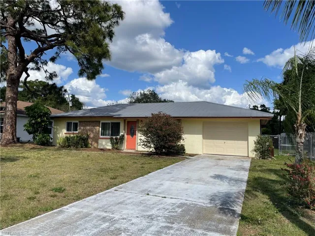 Single story home with stucco siding, driveway, an attached garage, a front lawn, and fence