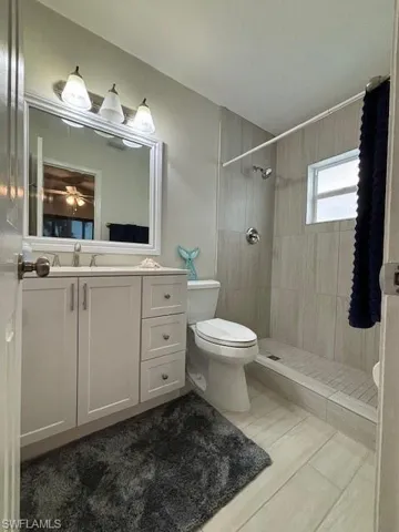 Bathroom with tile floors, tiled shower, toilet, and vanity