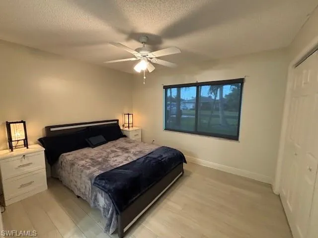 Bedroom featuring a textured ceiling, a closet, ceiling fan, and light hardwood / wood-style flooring