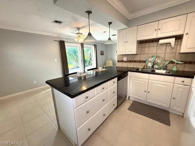Kitchen with kitchen peninsula, dishwasher, hanging light fixtures, tasteful backsplash, and white cabinets