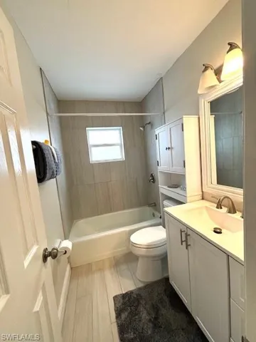 Full bathroom featuring hardwood / wood-style flooring, toilet, oversized vanity, and tiled shower / bath