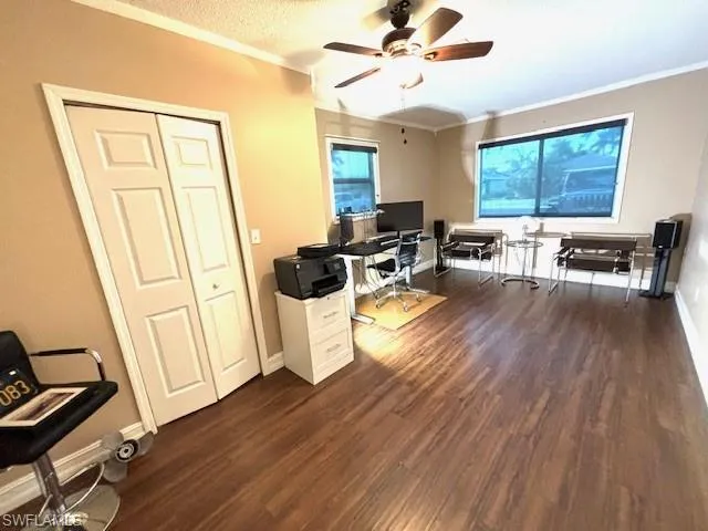 Office area with ceiling fan, dark hardwood / wood-style flooring, and ornamental molding