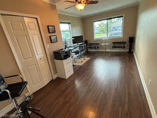 Office area featuring dark hardwood / wood-style flooring, ornamental molding, and ceiling fan