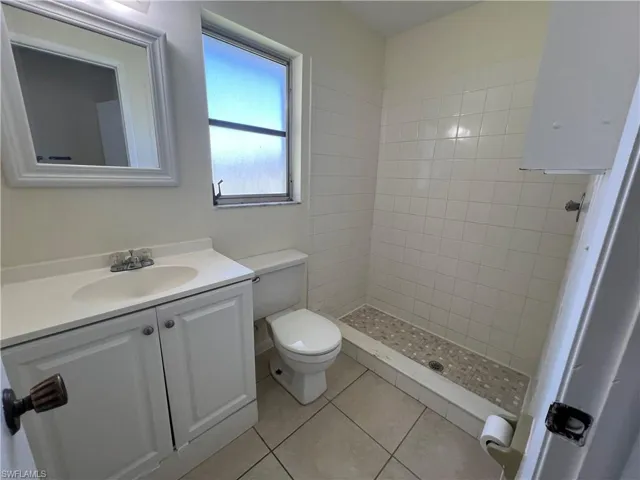 Master Bathroom with tiled shower, tile patterned floors, vanity, and toilet