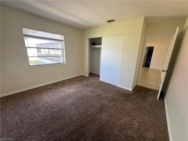 Guest bedroom with a textured ceiling, carpet flooring, and a closet