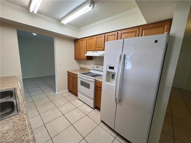 Kitchen with sink, white appliances, and light tile patterned floors