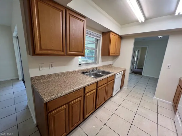 Kitchen with light tile patterned flooring, sink, and dishwasher