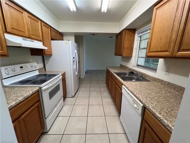 Kitchen featuring white appliances, sink, and light tile patterned flooring