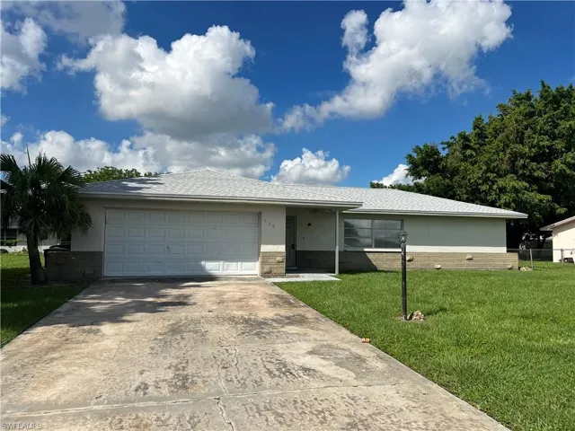 Single story home featuring a garage and a front lawn
