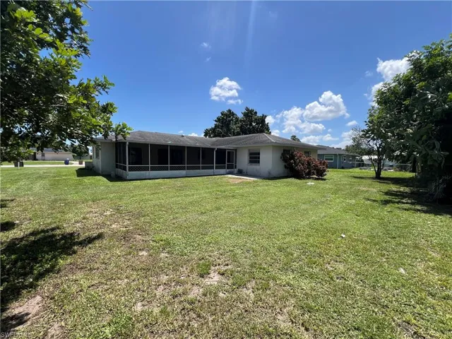 Rear view of house with a sunroom and a lawn