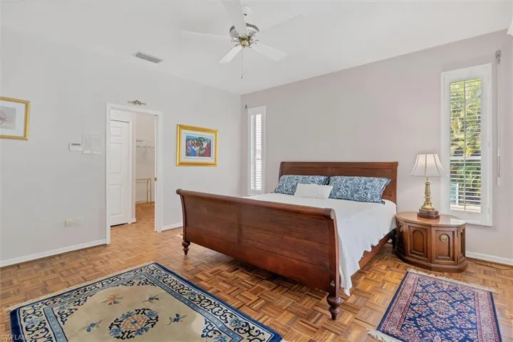 Bedroom featuring parquet floors, multiple windows, and ceiling fan