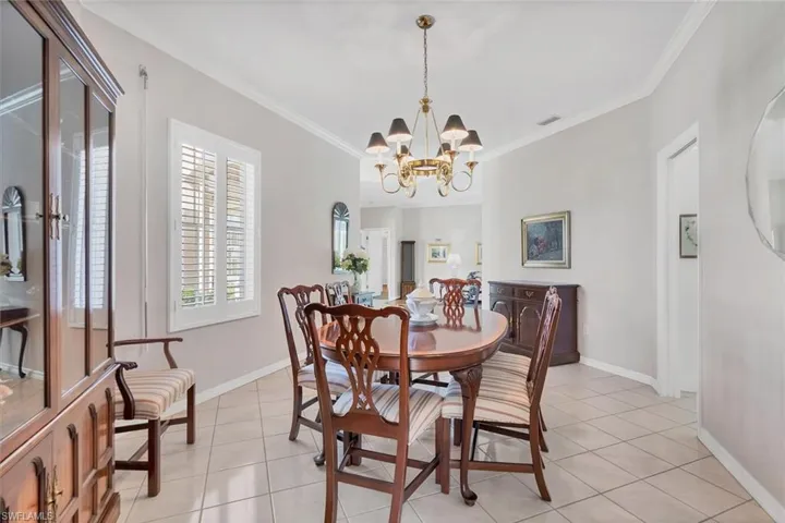 Dining area with ornamental molding, light tile patterned floors, and a chandelier