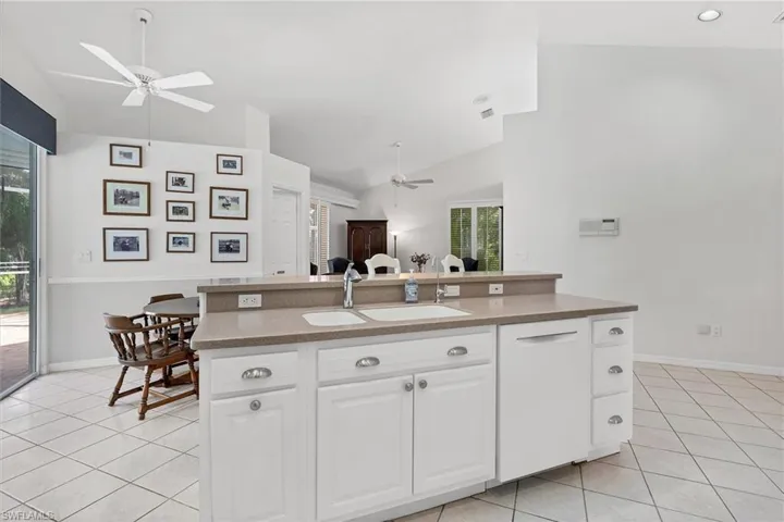 Kitchen featuring lofted ceiling, ceiling fan, sink, and white cabinetry