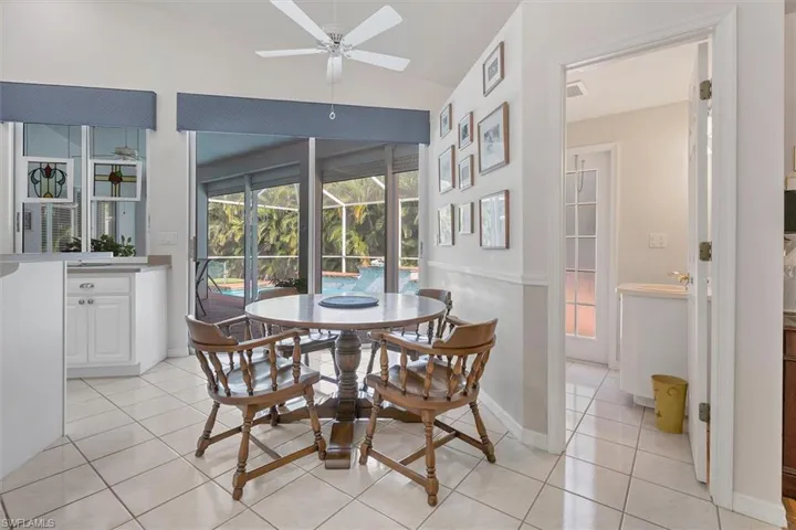 Dining area featuring vaulted ceiling, light tile patterned flooring, and ceiling fan