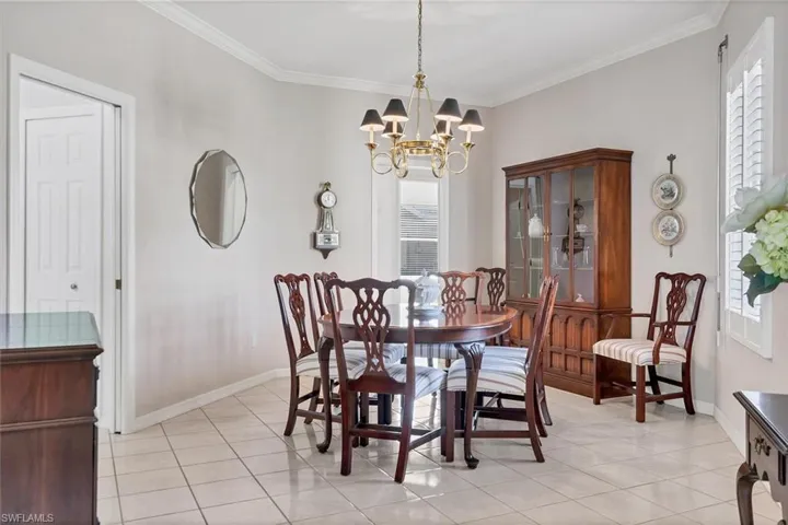 Dining room with an inviting chandelier, light tile patterned flooring, and ornamental molding
