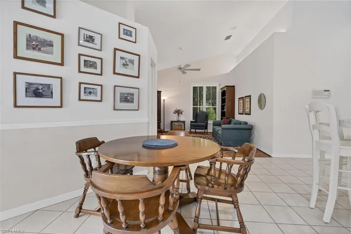 Dining space with ceiling fan, light tile patterned floors, and vaulted ceiling