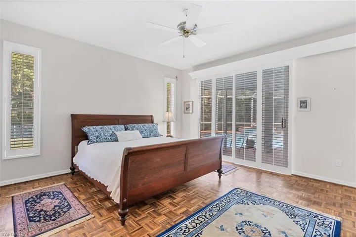 Bedroom featuring access to outside, dark parquet flooring, and ceiling fan