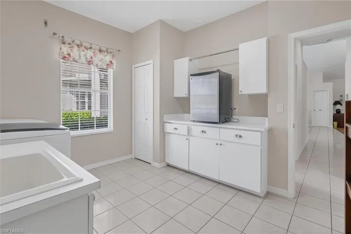 Kitchen featuring white cabinets, stainless steel fridge, light tile patterned floors, and sink