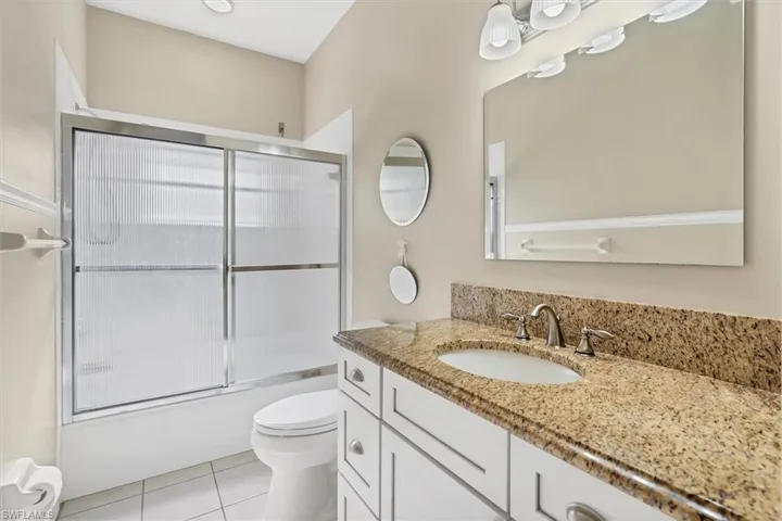 Full bathroom with combined bath / shower with glass door, vanity, toilet, and tile patterned floors