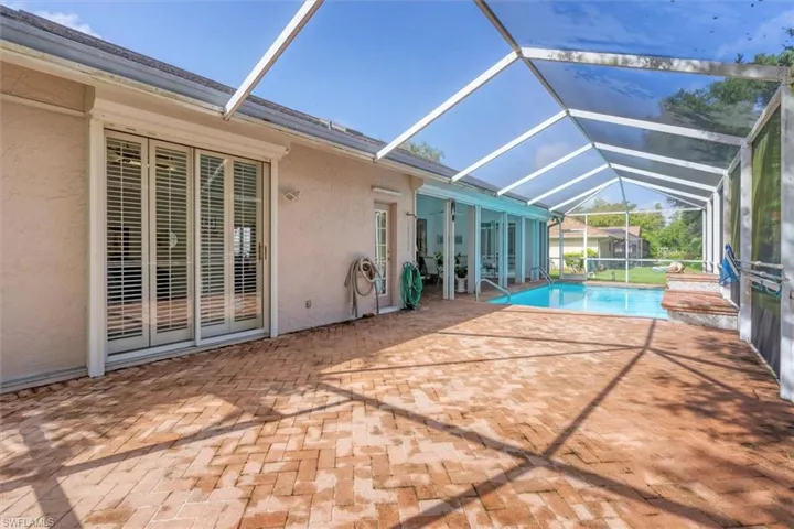View of pool featuring a patio and glass enclosure
