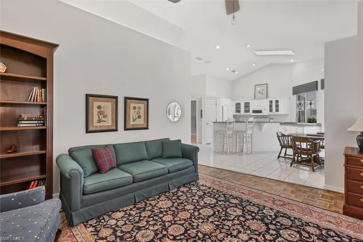 Living room featuring lofted ceiling, light parquet floors, and ceiling fan