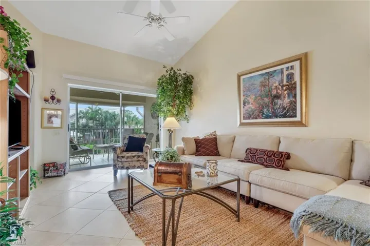 Living area with light tile patterned floors, a ceiling fan, and high vaulted ceiling