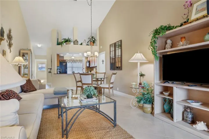 Living area featuring high vaulted ceiling, light tile patterned floors, and a chandelier