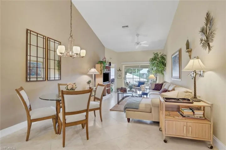 Dining space with ceiling fan, a chandelier, light tile patterned flooring, and a high ceiling
