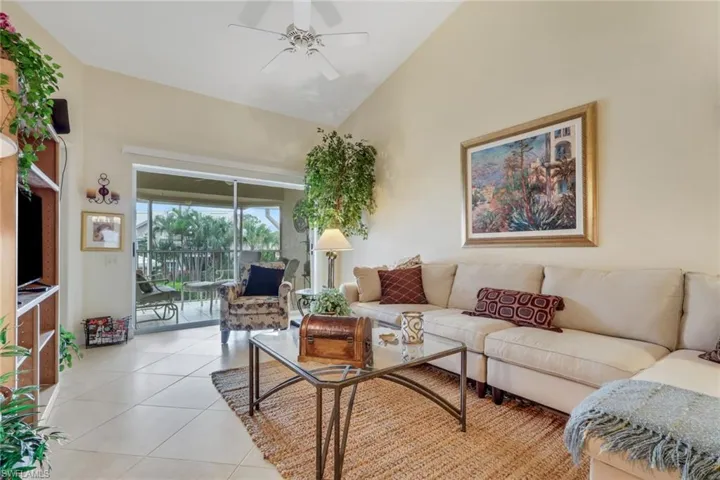 Living area featuring light tile patterned flooring, ceiling fan, and high vaulted ceiling