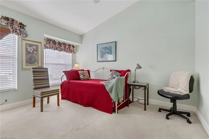 Carpeted bedroom featuring vaulted ceiling and ceiling fan