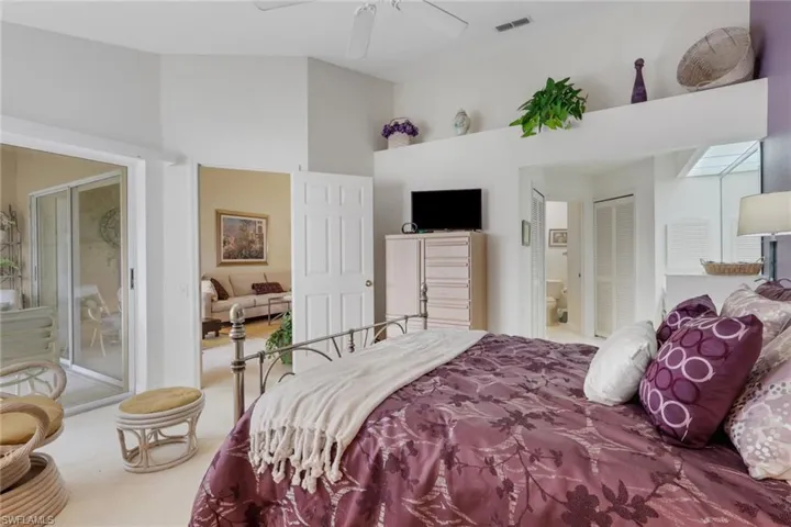 Carpeted bedroom with ensuite bath, a closet, a ceiling fan, and a high ceiling