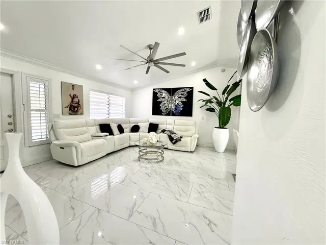 Living area featuring lofted ceiling, crown molding, recessed lighting, light marble finish floors, and ceiling fan