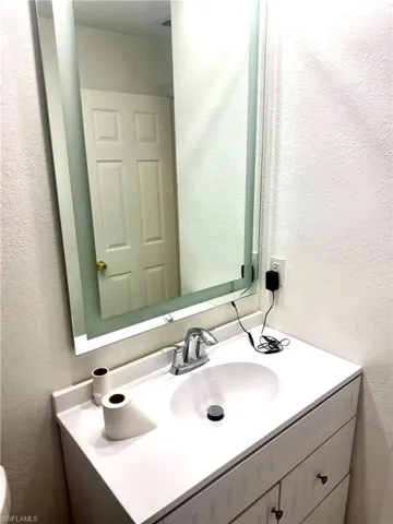 Bathroom featuring a textured wall and vanity