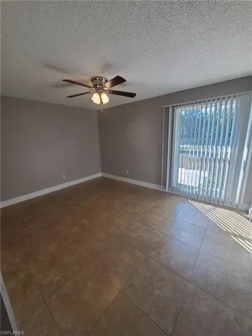 Spare room featuring ceiling fan, a textured ceiling, and tile patterned floors