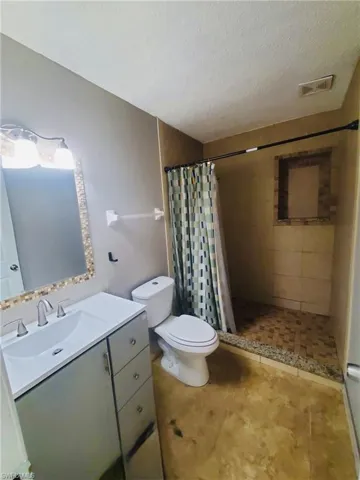 Full bathroom featuring a shower stall, vanity, and a textured ceiling