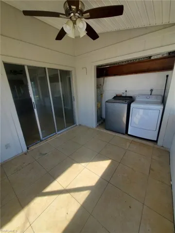 Laundry area with light tile patterned floors, a ceiling fan, washing machine and clothes dryer, water heater, and a vaulted wood ceiling