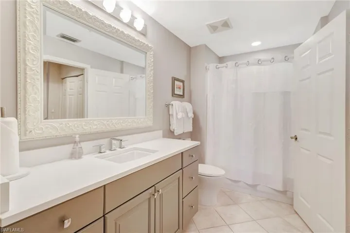 Bathroom with light tile patterned flooring, vanity, and shower / bath combination with curtain