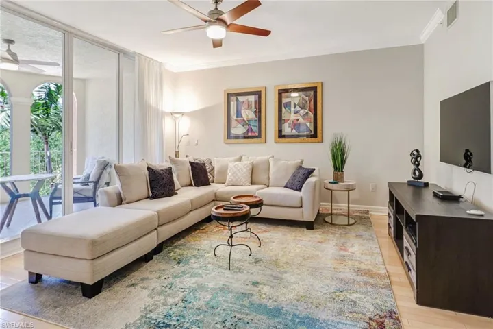 Living room featuring light wood-style floors, ornamental molding, expansive windows, and ceiling fan