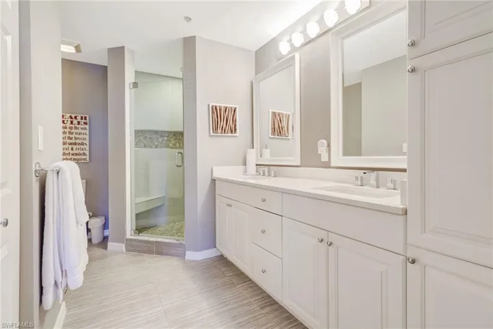 Full bathroom with double vanity, a stall shower, and light tile patterned floors