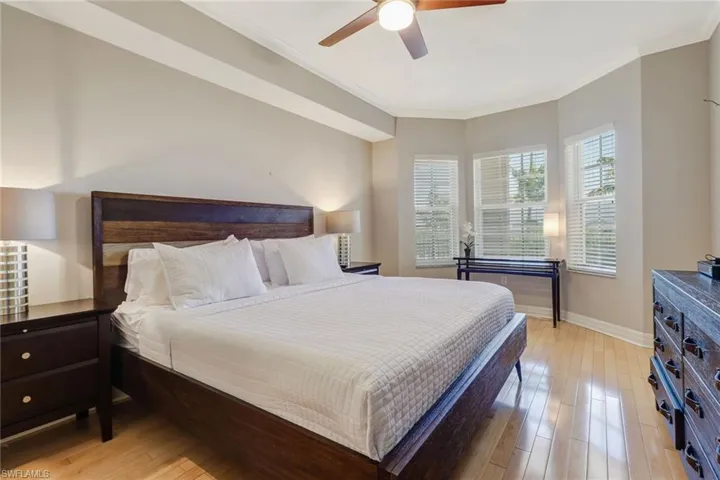 Bedroom featuring ornamental molding, light wood-style flooring, and a ceiling fan