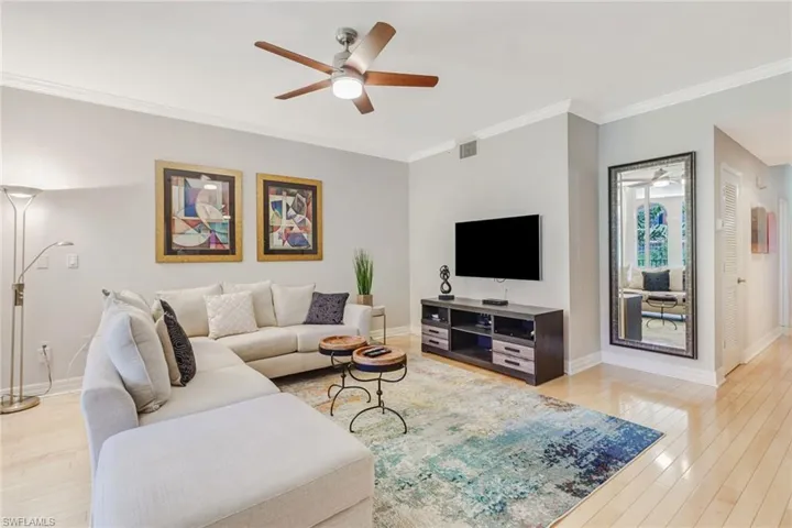 Living room with ornamental molding, a ceiling fan, and light wood finished floors