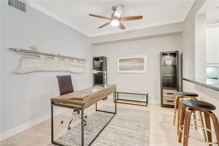 Office area with crown molding, light wood-style flooring, and a ceiling fan