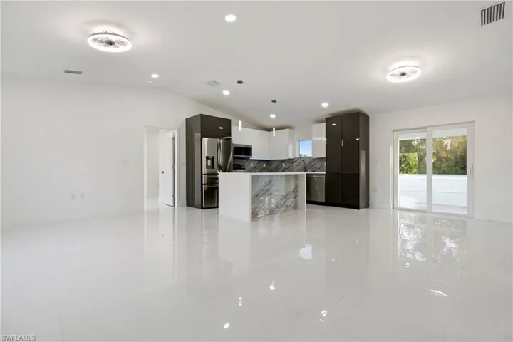 Kitchen featuring appliances with stainless steel finishes, vaulted ceiling, and light tile patterned flooring